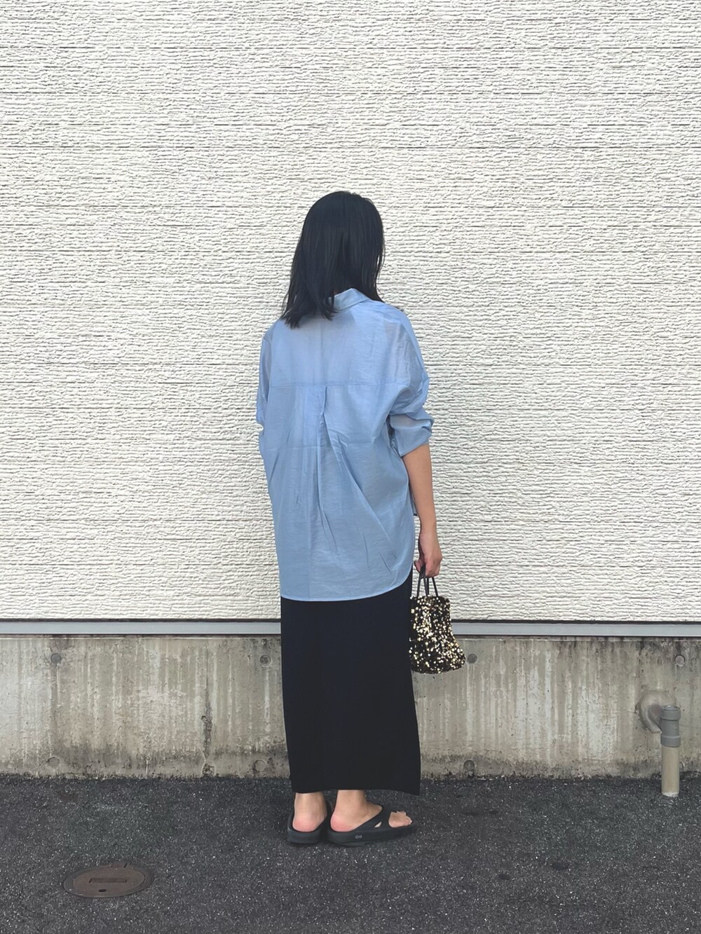 ブルー系のシャツ/ブラウス、ブラック系のスカート、ゴールド系のショルダーバッグを着用したレディースの夏コーディネートの2枚目の写真