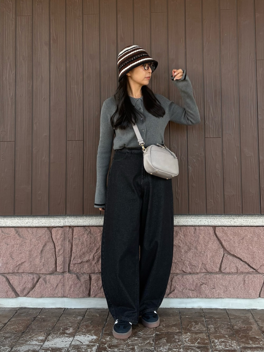 グレー系のニット/セーター、ブラック系のデニムパンツ、グレー系のショルダーバッグを着用したレディースの冬コーディネートの6枚目の写真