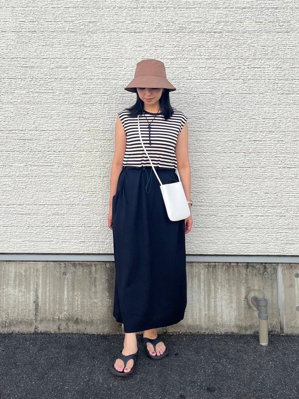 ブラック系のワンピース、ホワイト系のショルダーバッグ、ブラウン系のハットを着用したレディースの夏コーディネートの4枚目の写真