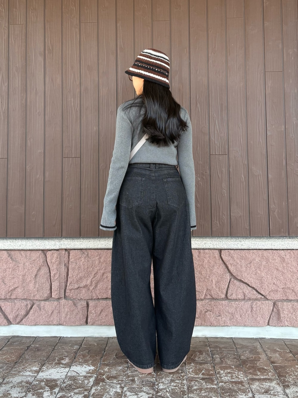 グレー系のニット/セーター、ブラック系のデニムパンツ、グレー系のショルダーバッグを着用したレディースの冬コーディネートの4枚目の写真