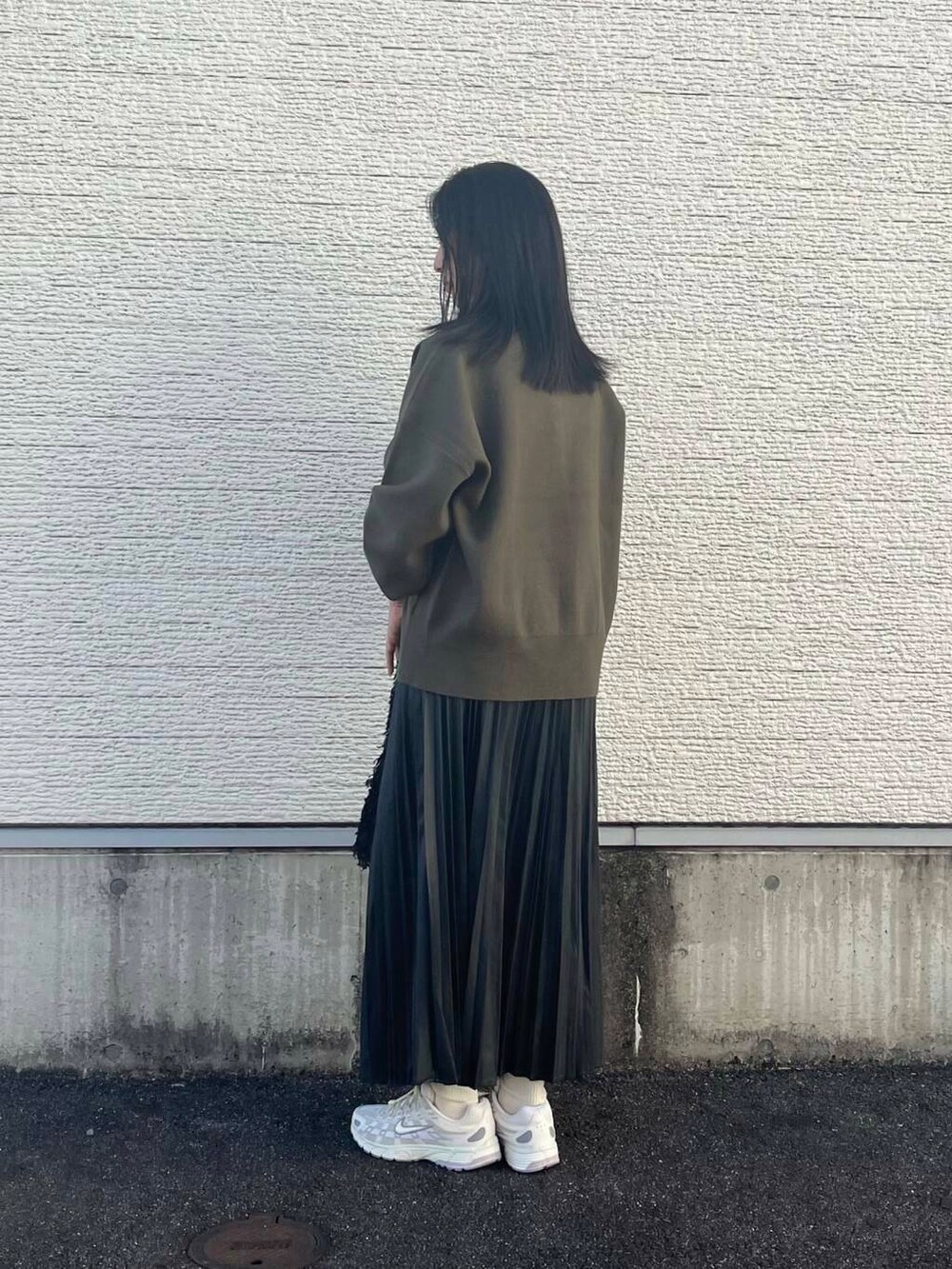 ブラック系のショルダーバッグ、グリーン系のニット/セーター、ホワイト系のスニーカーを着用したレディースの秋コーディネートの2枚目の写真