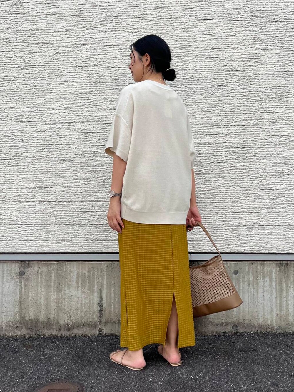 ベージュ系のショルダーバッグ、ホワイト系のニット/セーター、イエロー系のスカートを着用したレディースの夏コーディネートの2枚目の写真