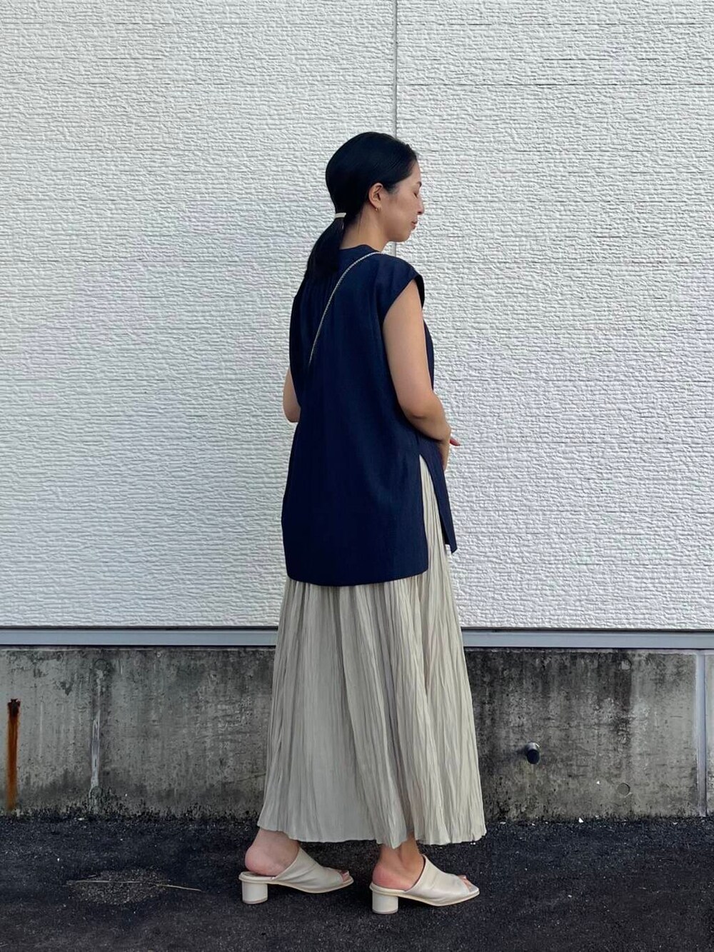 ゴールド系のショルダーバッグ、ベージュ系のスカート、ブルー系のシャツ/ブラウスを着用したレディースの夏コーディネートの2枚目の写真