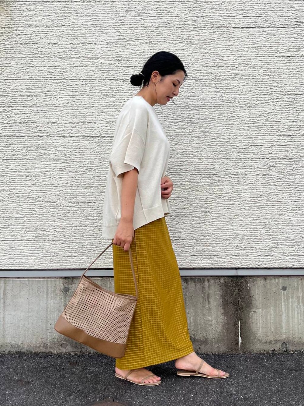 ベージュ系のショルダーバッグ、ホワイト系のニット/セーター、イエロー系のスカートを着用したレディースの夏コーディネートの4枚目の写真