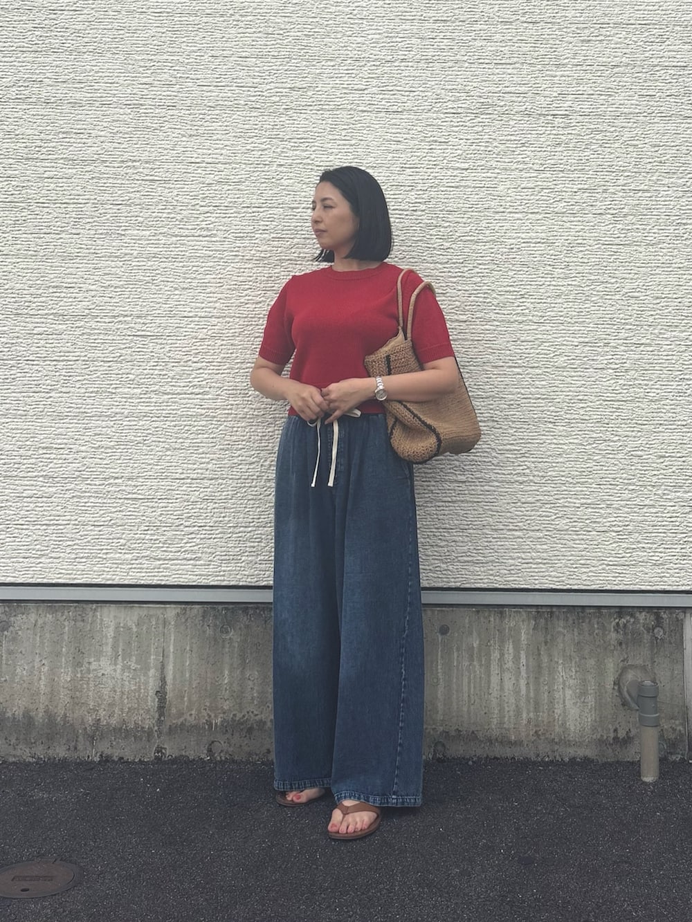 レッド系のニット/セーター、ブルー系のデニムパンツ、ベージュ系のトートバッグを着用したレディースの夏コーディネートの4枚目の写真