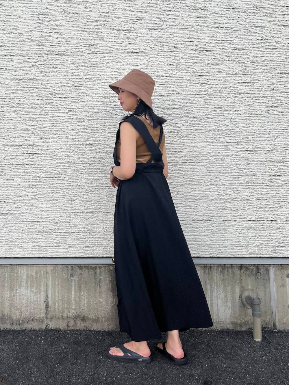 ゴールド系のショルダーバッグ、ブラック系のワンピース、ベージュ系のタンクトップを着用したレディースの夏コーディネートの3枚目の写真