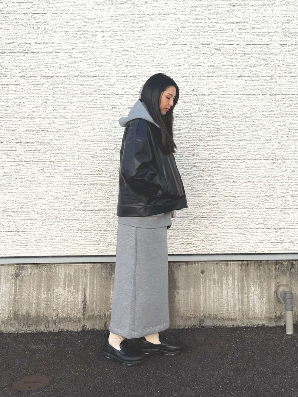 グレー系のスカート、ブラック系のスニーカー、グレー系のパーカーを着用したレディースの春コーディネートの2枚目の写真
