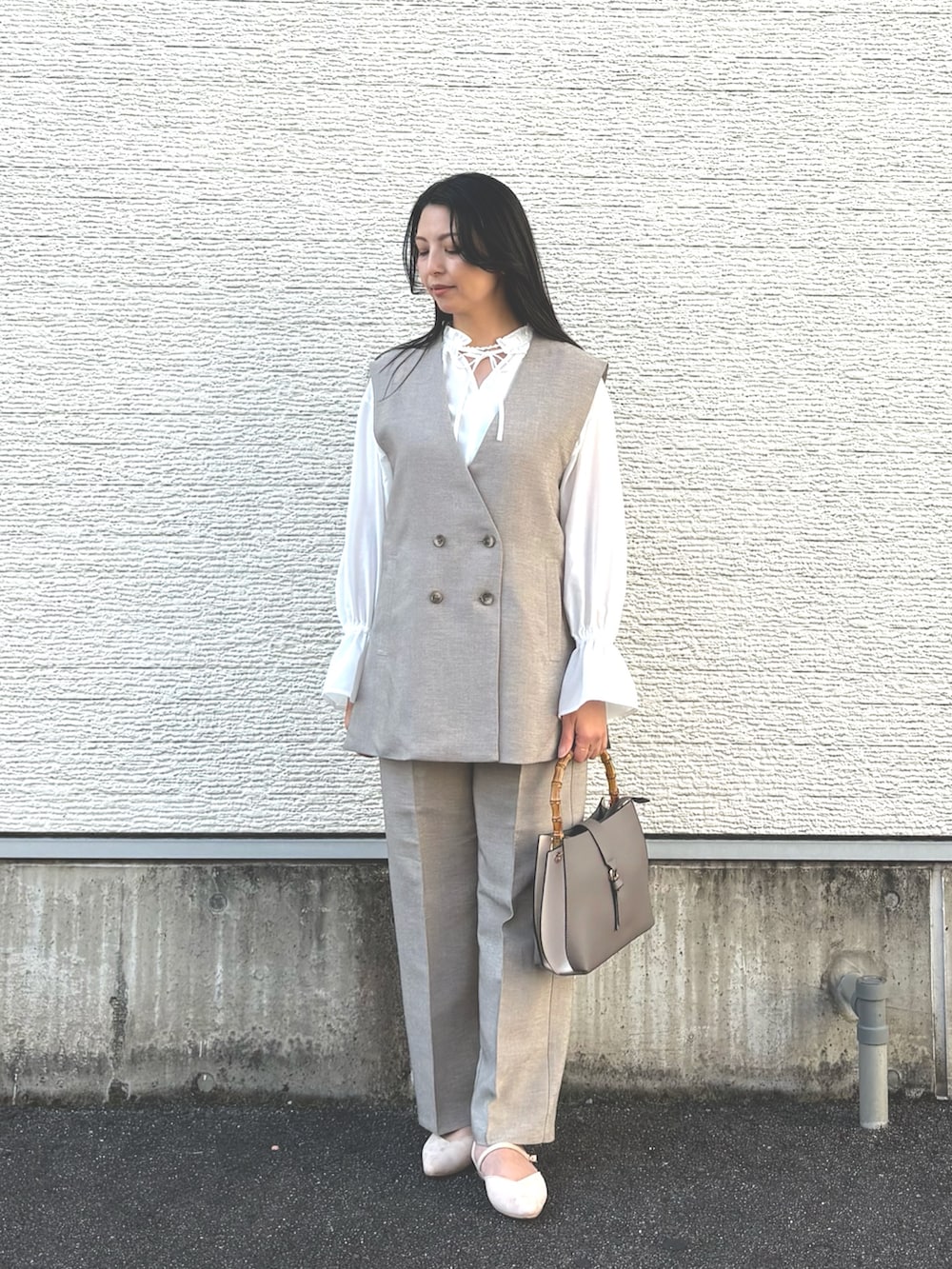 その他のハンドバッグ、ホワイト系のパンプス、ベージュ系のセットアップを着用したレディースの冬コーディネートの6枚目の写真