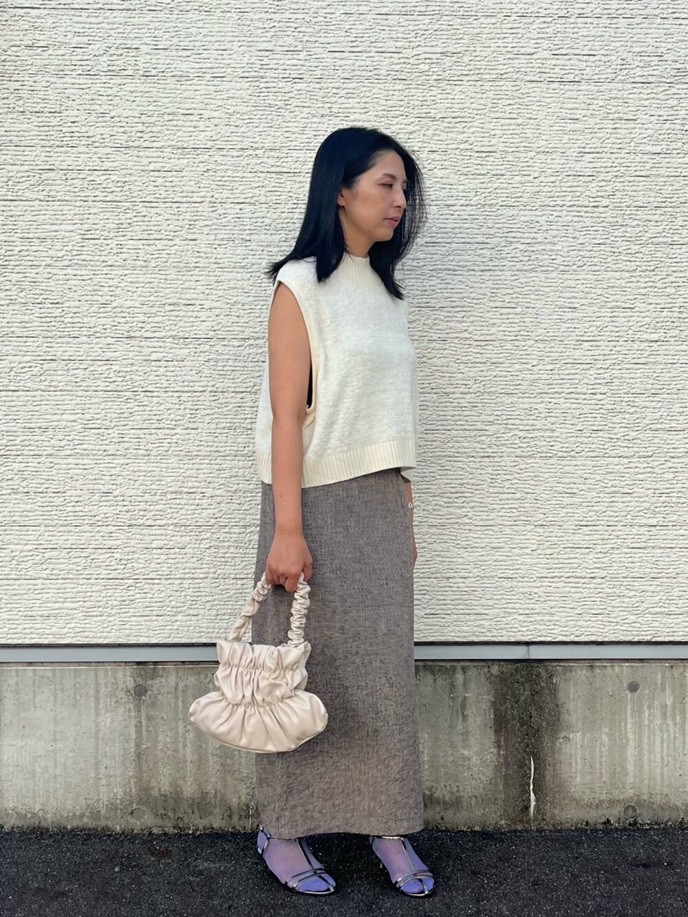 ホワイト系のニット/セーター、ベージュ系のスカート、ホワイト系のハンドバッグを着用したレディースの秋コーディネートの2枚目の写真