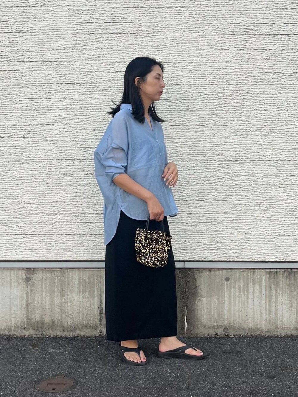 ゴールド系のショルダーバッグ、ブルー系のシャツ/ブラウス、ブラック系のスカートを着用したレディースの夏コーディネートの4枚目の写真