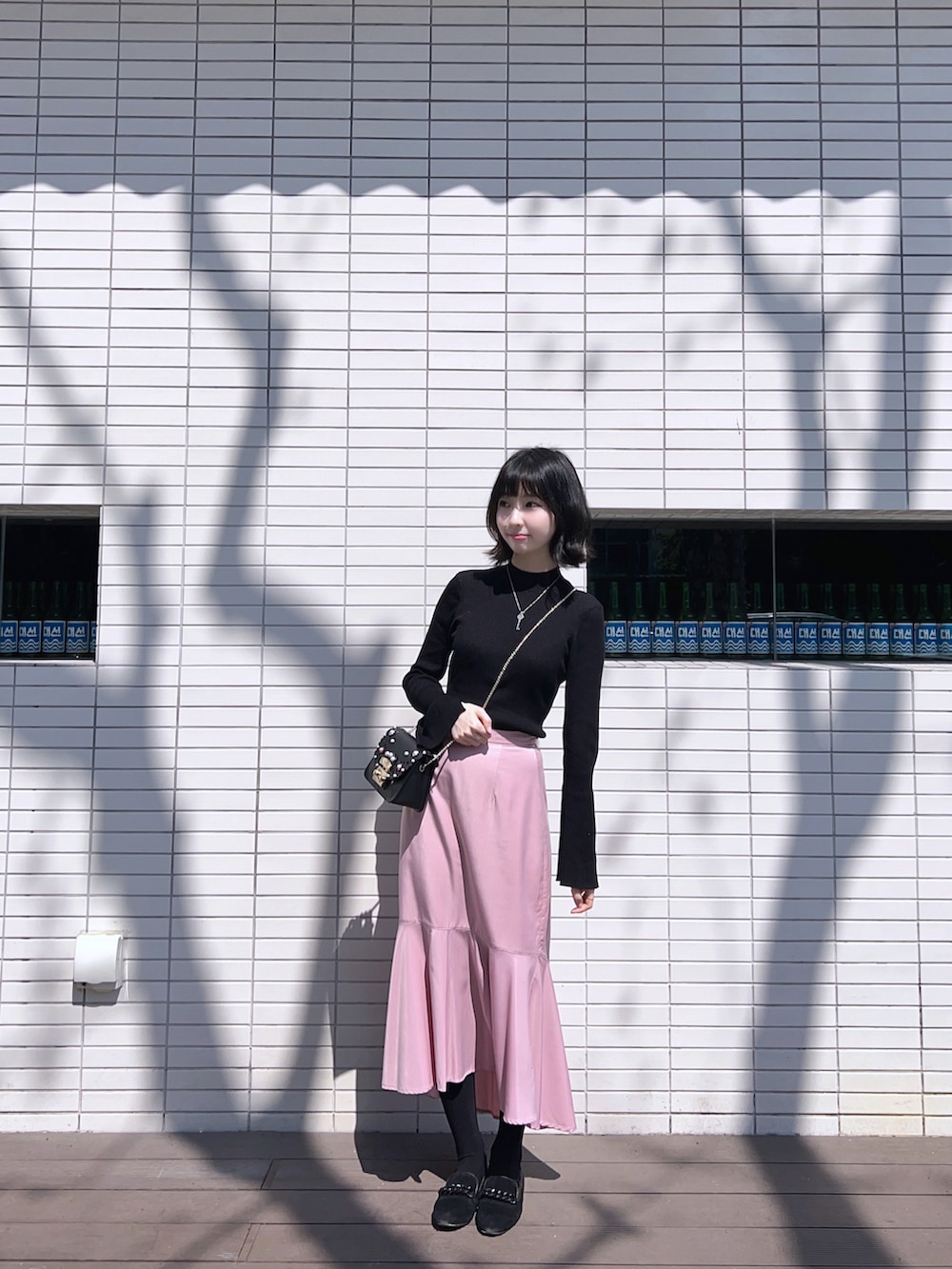 ピンク系のスカート、ブラック系のブルゾンを着用したレディースの春コーディネートの2枚目の写真
