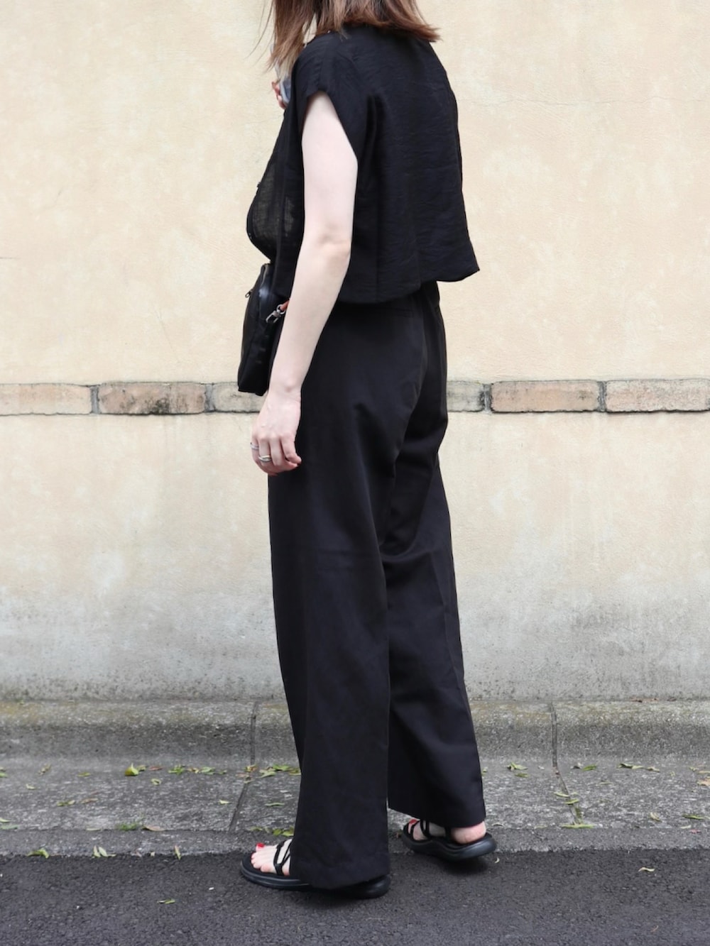 ブラック系のキャミソール、ブラック系のパンツ、ブラック系のサンダルを着用したレディースの夏コーディネートの3枚目の写真