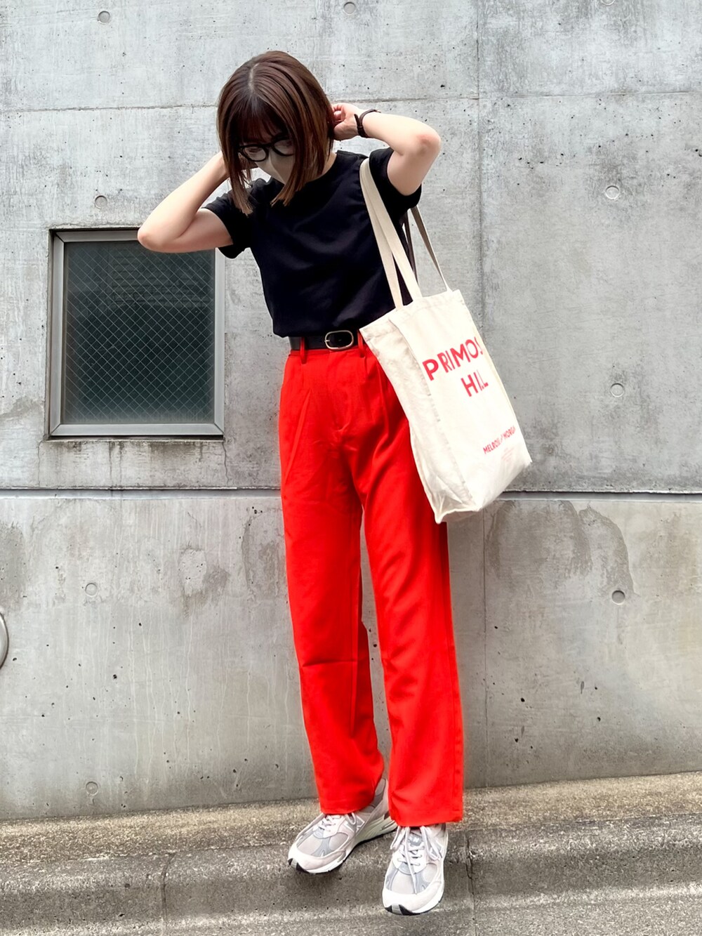 オレンジ系のスラックス、ブラック系のTシャツ/カットソー、グレー系のスニーカーを着用したレディースの夏コーディネートの2枚目の写真