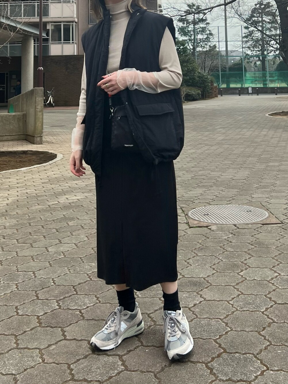 ベージュ系のTシャツ/カットソー、ブラック系のジャンパースカート、ブラック系のバッグを着用したレディースの春コーディネートの2枚目の写真