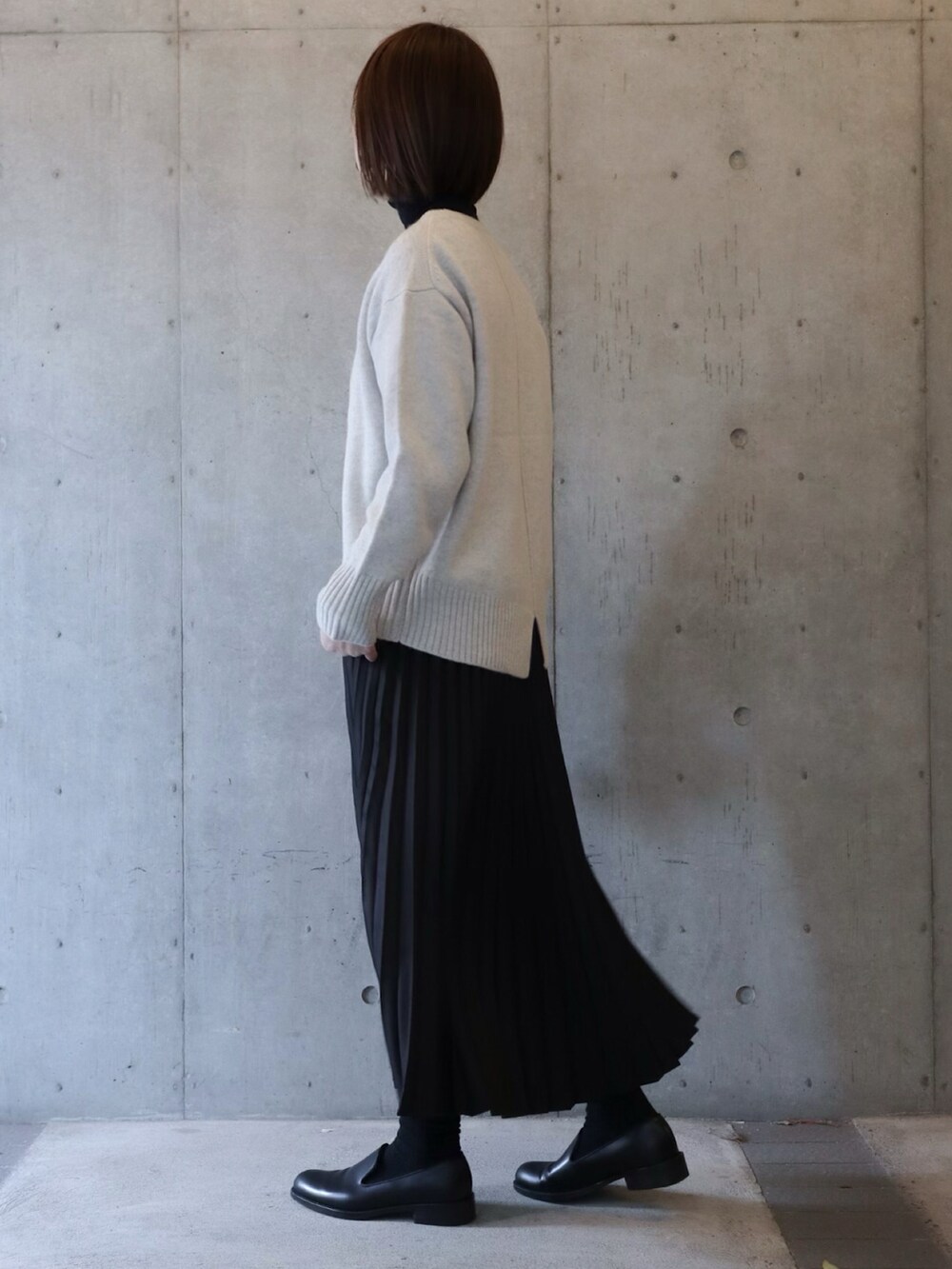 グレー系のニット/セーター、ブラック系のスカート、ブラック系のシューズを着用したレディースの冬コーディネートの3枚目の写真