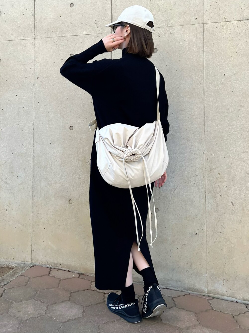 ブラック系のワンピース、ホワイト系のバッグ、ブラック系のスニーカーを着用したレディースの冬コーディネートの4枚目の写真