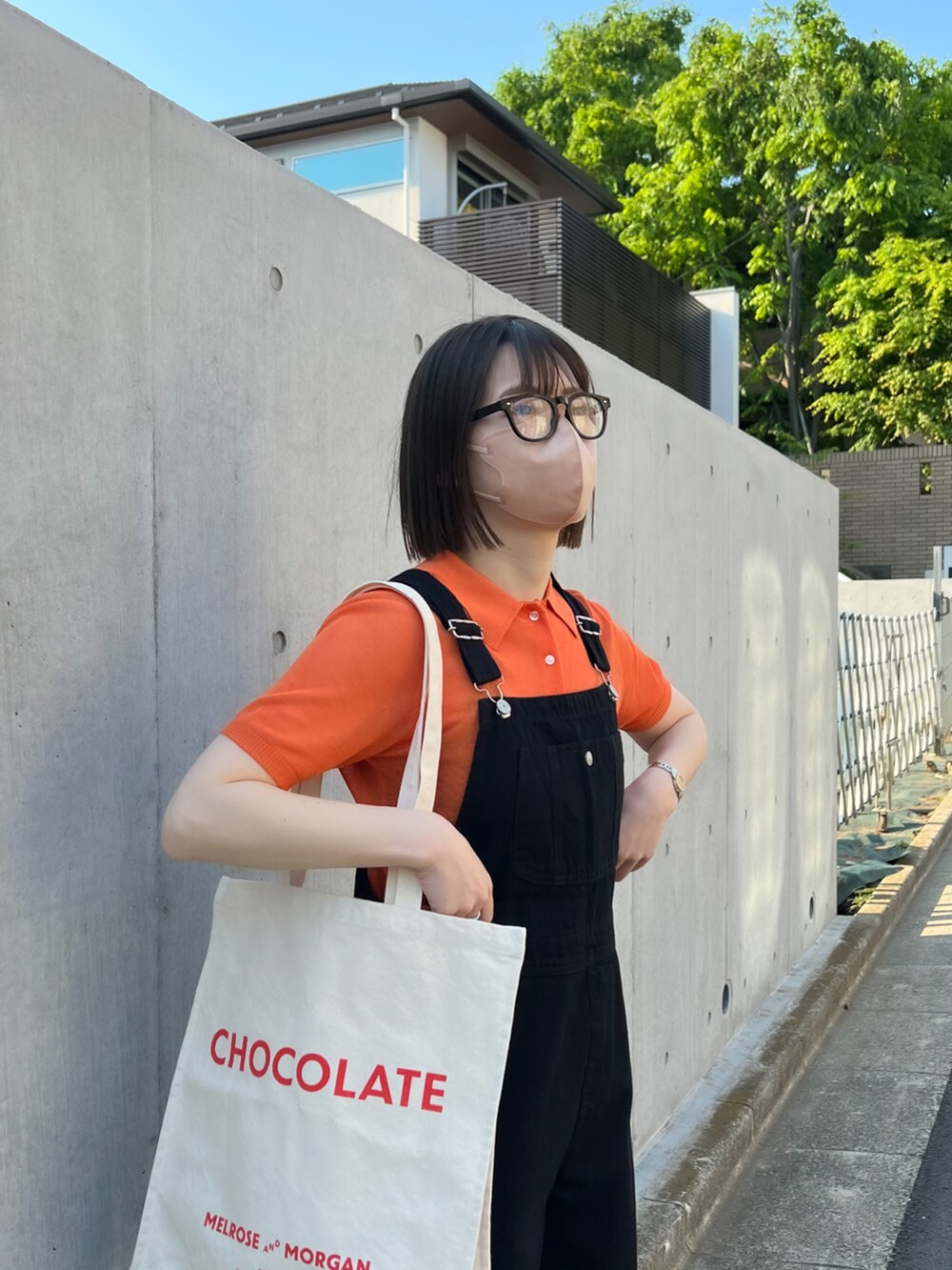 オレンジ系のポロシャツ、ブラック系のサロペット/オーバーオール、ホワイト系のスニーカーを着用したレディースの春コーディネートの2枚目の写真