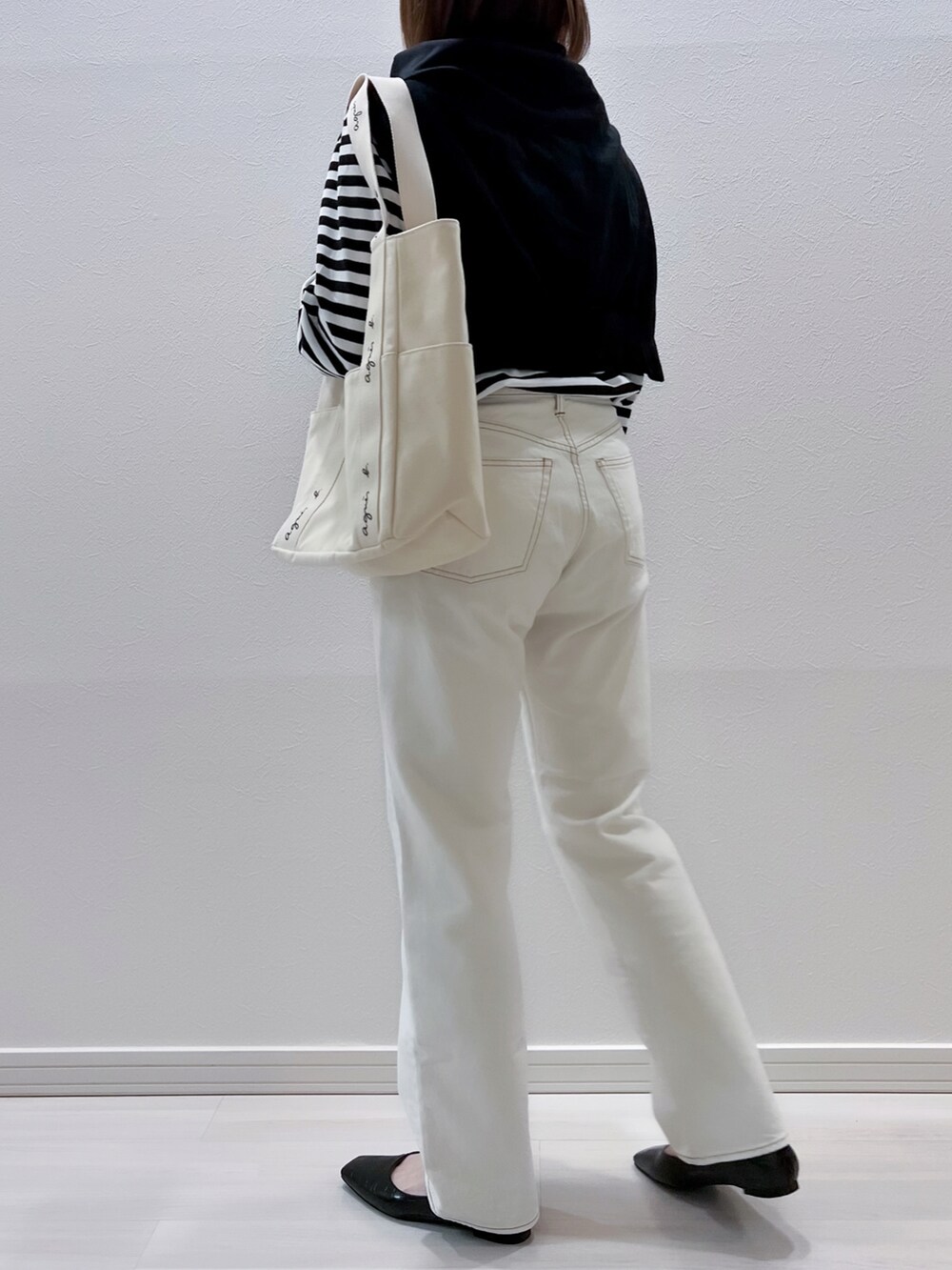 ブラック系のTシャツ/カットソー、ホワイト系のデニムパンツ、ブラック系のパンプスを着用したレディースの春コーディネートの3枚目の写真