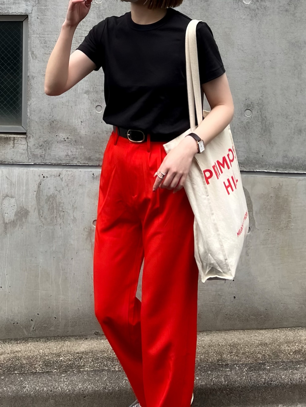 オレンジ系のスラックス、ブラック系のTシャツ/カットソー、グレー系のスニーカーを着用したレディースの夏コーディネートの3枚目の写真