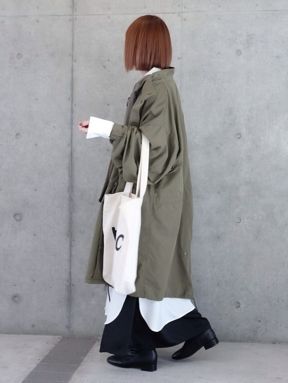 グリーン系のモッズコート、グリーン系のベスト、ブラック系のワンピースを着用したレディースの秋コーディネートの2枚目の写真