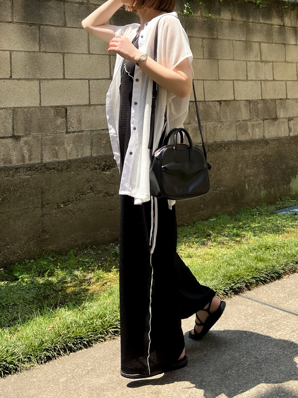 ブラック系のサロペット/オーバーオール、ホワイト系のシャツ/ブラウス、ブラック系のサンダルを着用したレディースの夏コーディネートの3枚目の写真