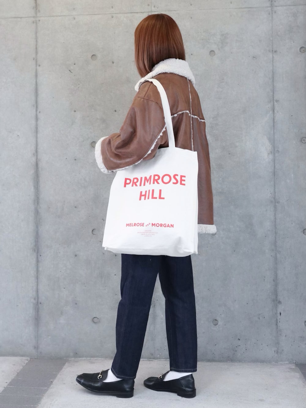 ブラウン系のムートンコート、ブルー系のデニムパンツ、ホワイト系のニット/セーターを着用したレディースの秋コーディネートの2枚目の写真