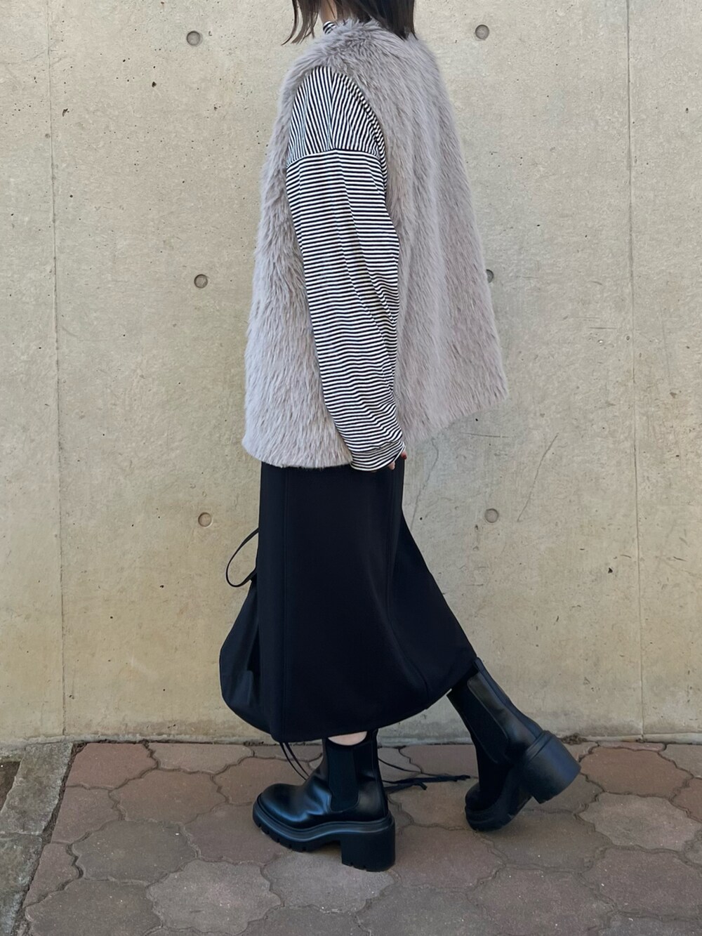 ブラック系のバッグ、ブラック系のジャンパースカート、ブラック系のブーツを着用したレディースの冬コーディネートの3枚目の写真