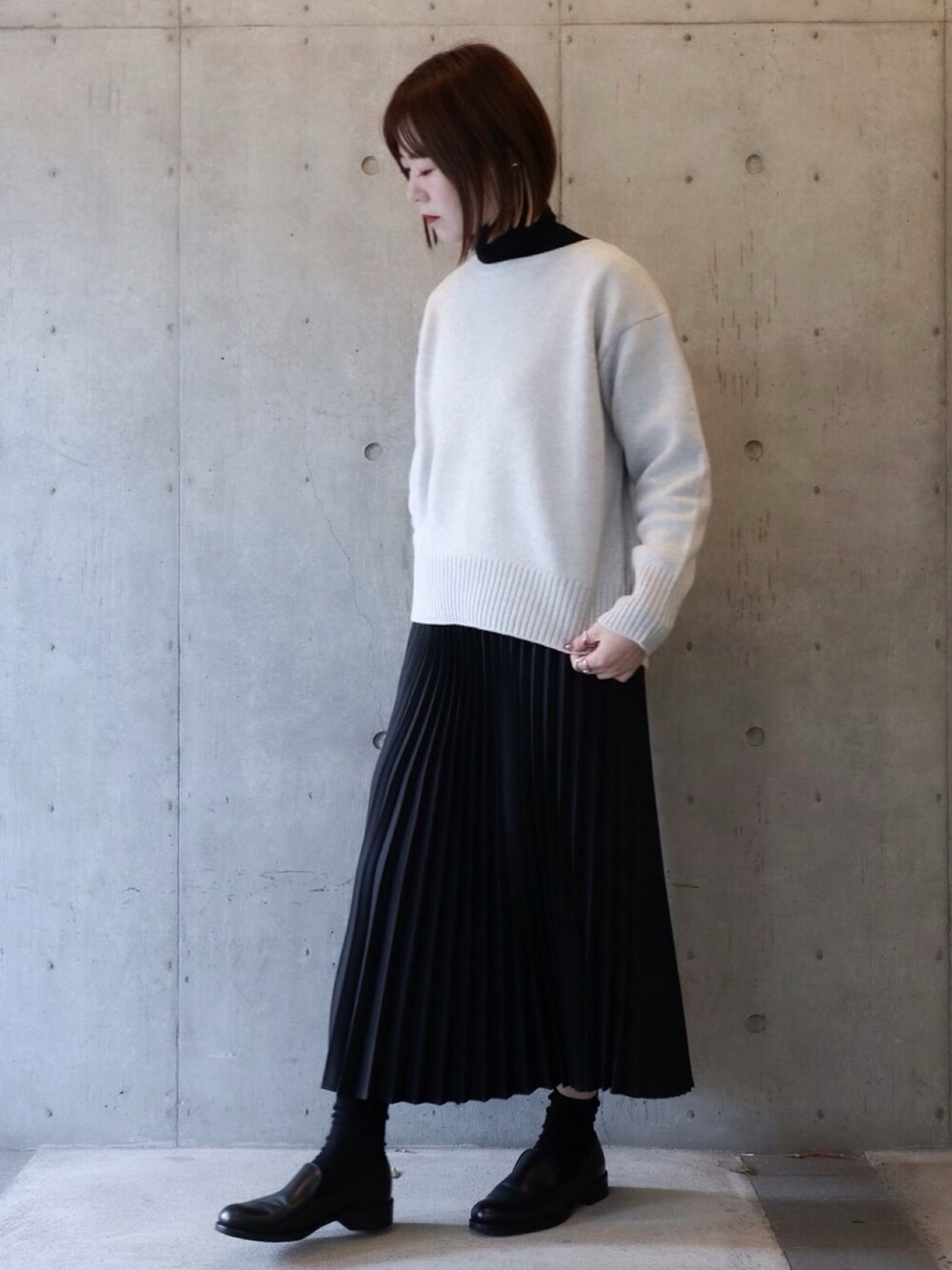 グレー系のニット/セーター、ブラック系のスカート、ブラック系のシューズを着用したレディースの冬コーディネートの2枚目の写真