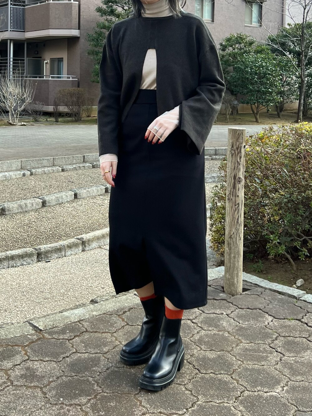 ベージュ系のTシャツ/カットソー、ブラック系のニット/セーター、ブラック系のジャンパースカートを着用したレディースの冬コーディネートの2枚目の写真