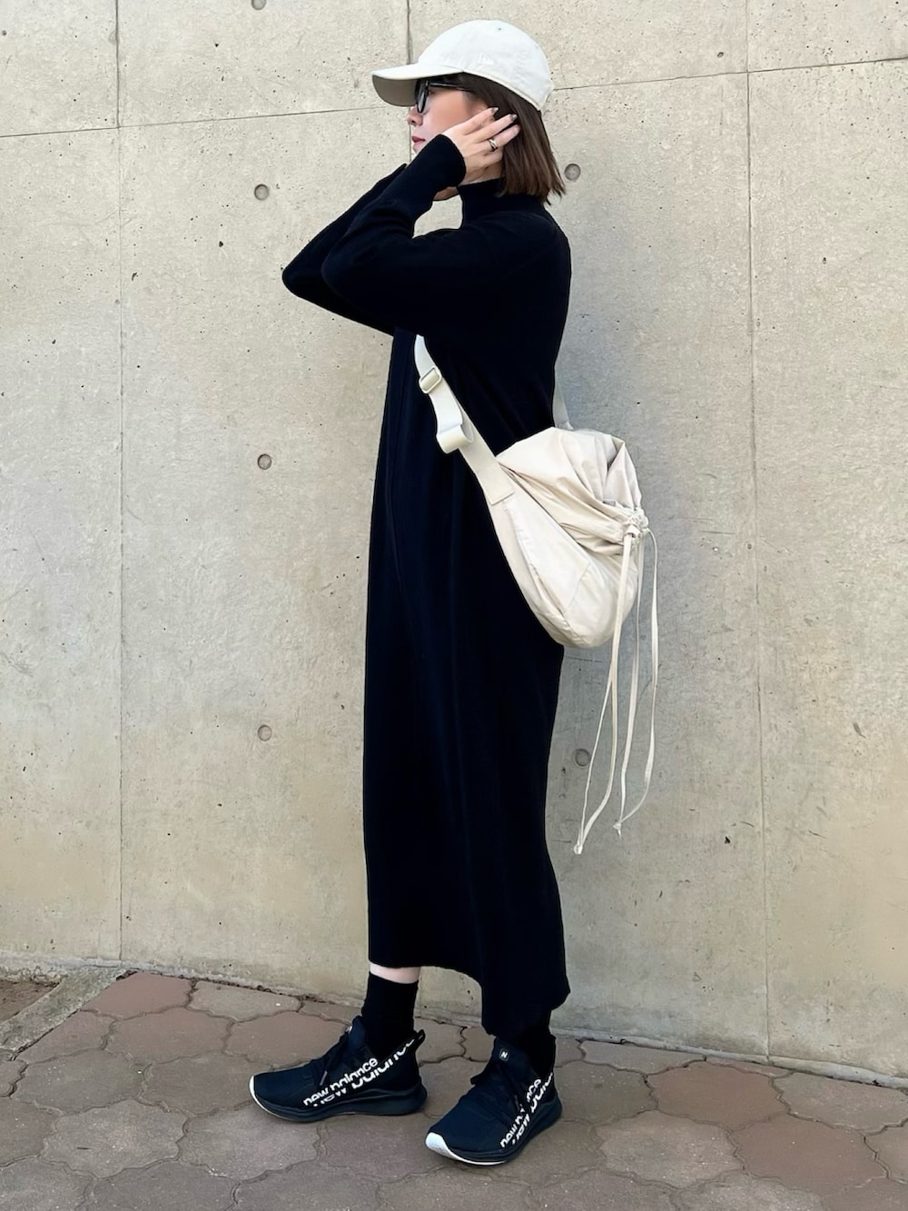 ブラック系のワンピース、ホワイト系のバッグ、ブラック系のスニーカーを着用したレディースの冬コーディネートの2枚目の写真