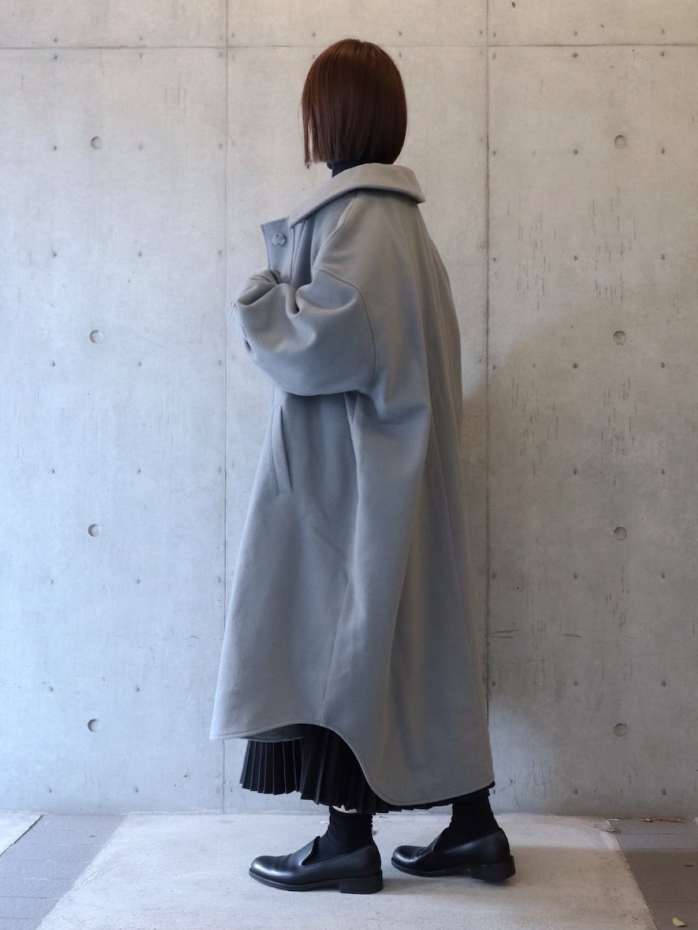 グレー系のダウンジャケット/コート、グレー系のニット/セーター、ブラック系のスカートを着用したレディースの冬コーディネートの2枚目の写真