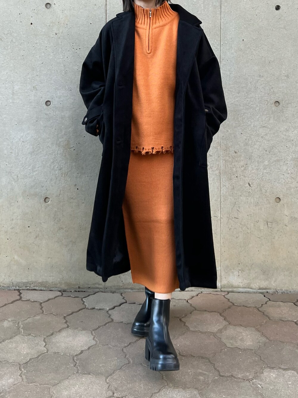 オレンジ系のニット/セーター、オレンジ系のスカート、ブラック系のバッグを着用したレディースの秋コーディネートの3枚目の写真