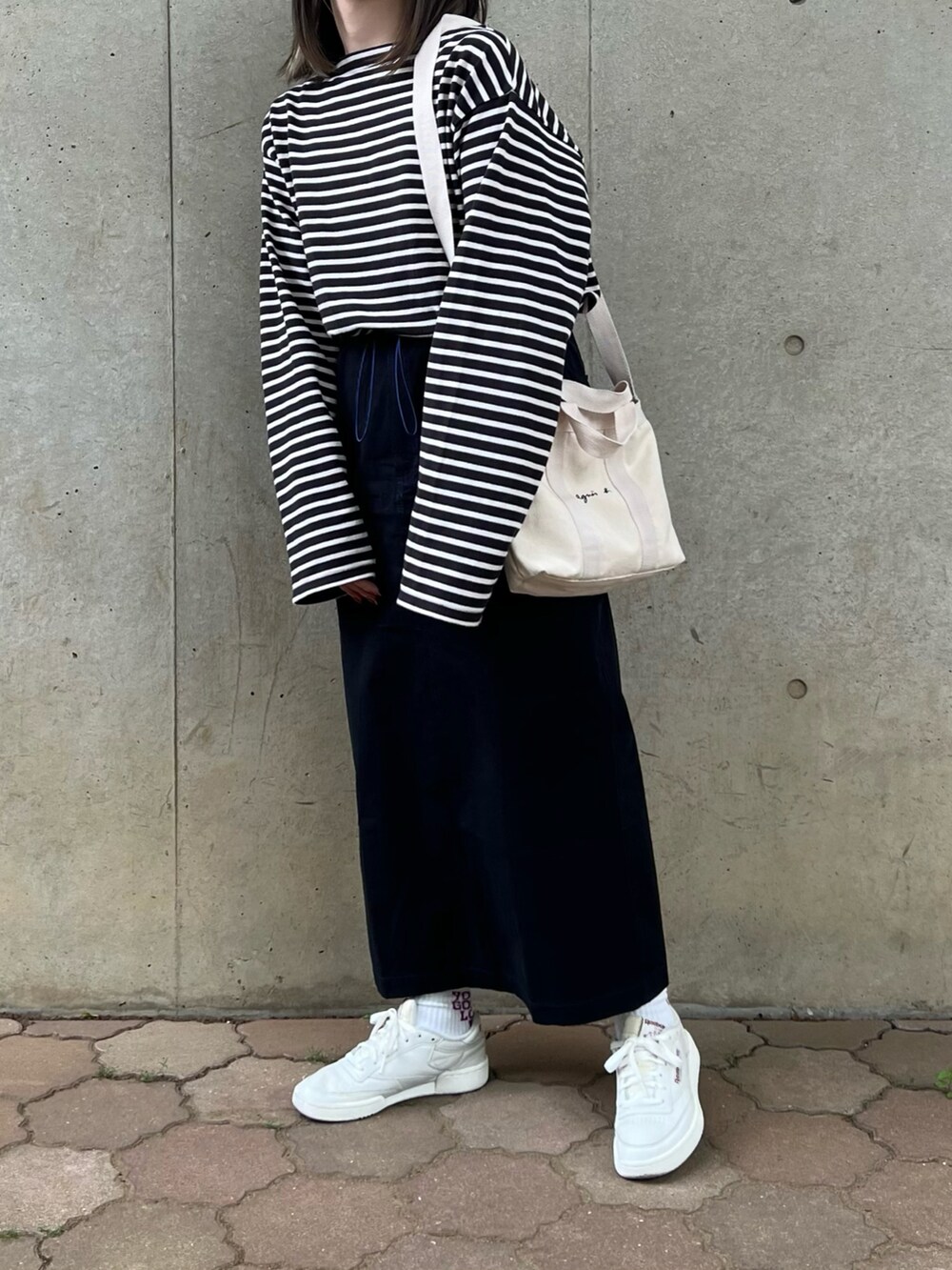ホワイト系のトートバッグ、ホワイト系のスニーカー、ブラック系のスカートを着用したレディースの春コーディネートの2枚目の写真
