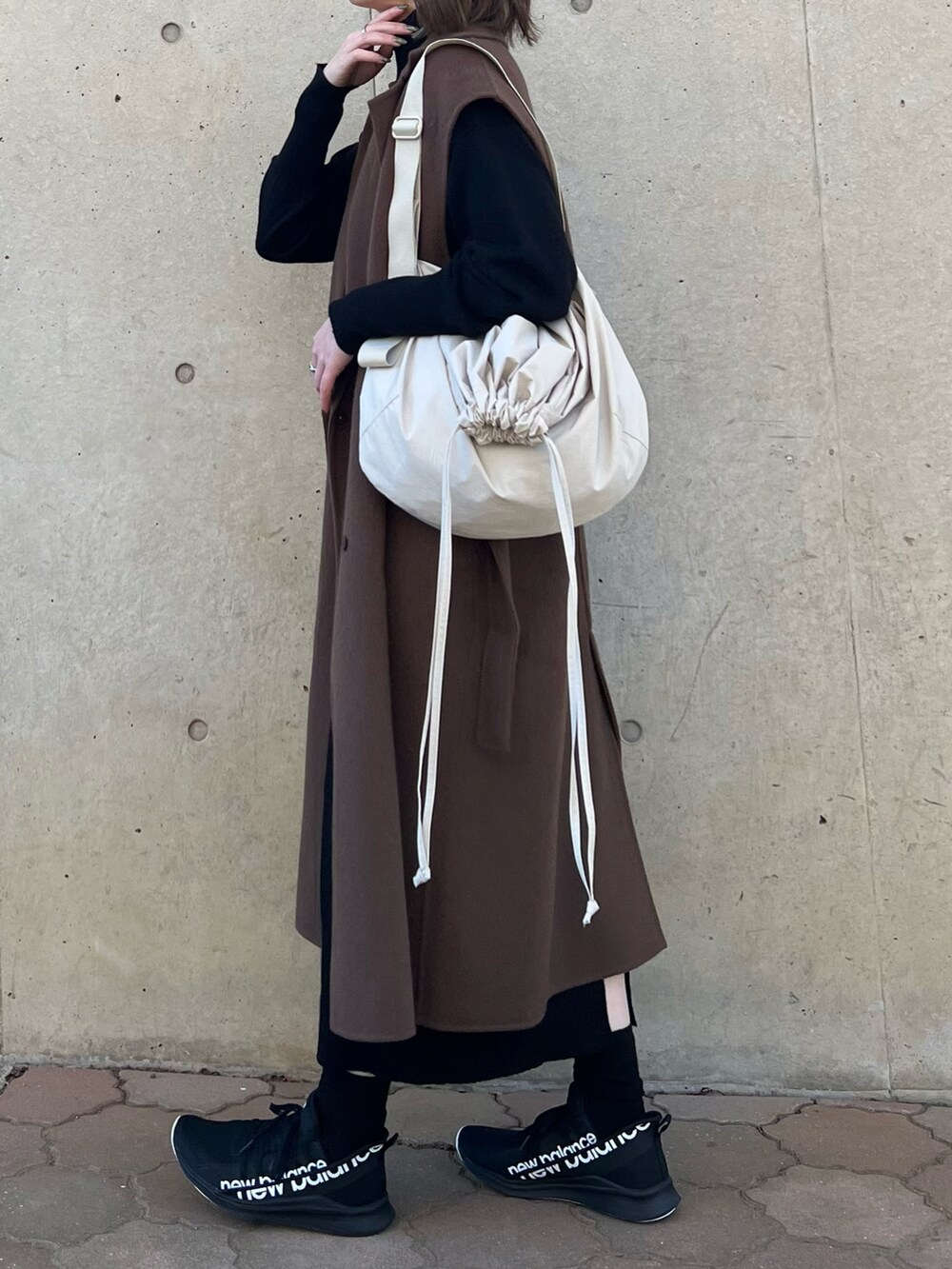 ブラック系のワンピース、ブラウン系のチェスターコート、ホワイト系のバッグを着用したレディースの秋コーディネートの3枚目の写真