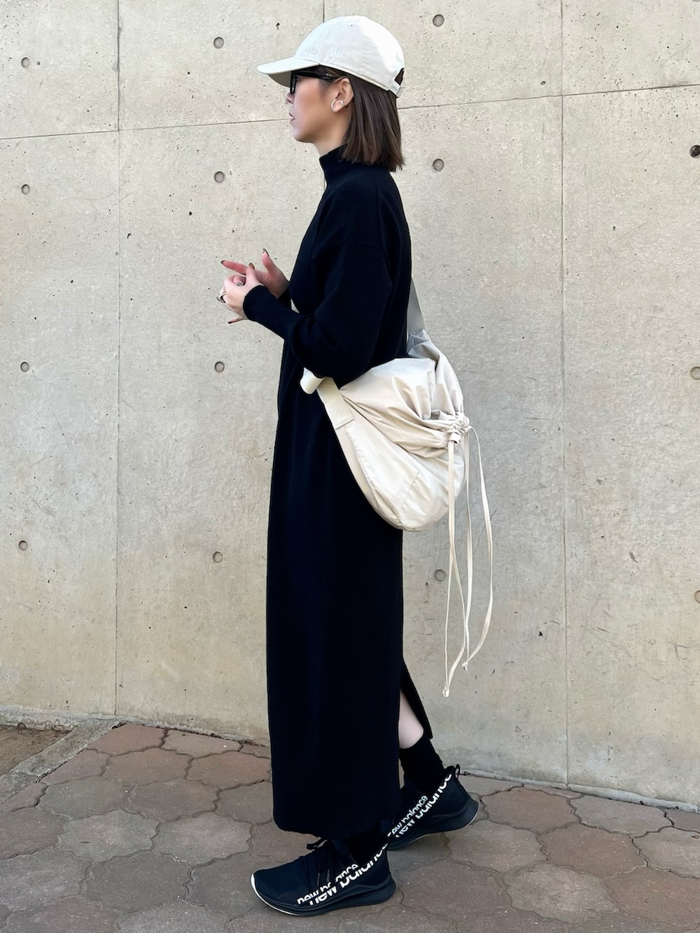 ブラック系のワンピース、ホワイト系のバッグ、ブラック系のスニーカーを着用したレディースの冬コーディネートの3枚目の写真