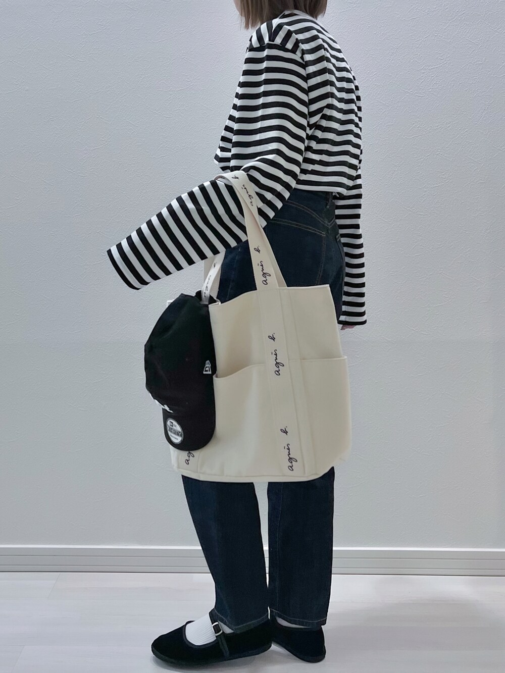 ブラック系のTシャツ/カットソー、ベージュ系のトートバッグ、ブルー系のデニムパンツを着用したレディースの春コーディネートの2枚目の写真