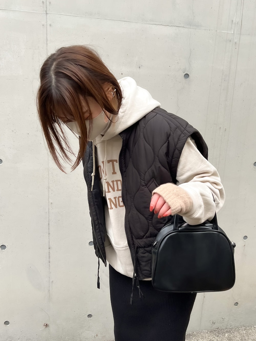 グレー系のパーカー、ブラック系のダウンベスト、ブラック系のボストンバッグを着用したレディースの冬コーディネートの2枚目の写真