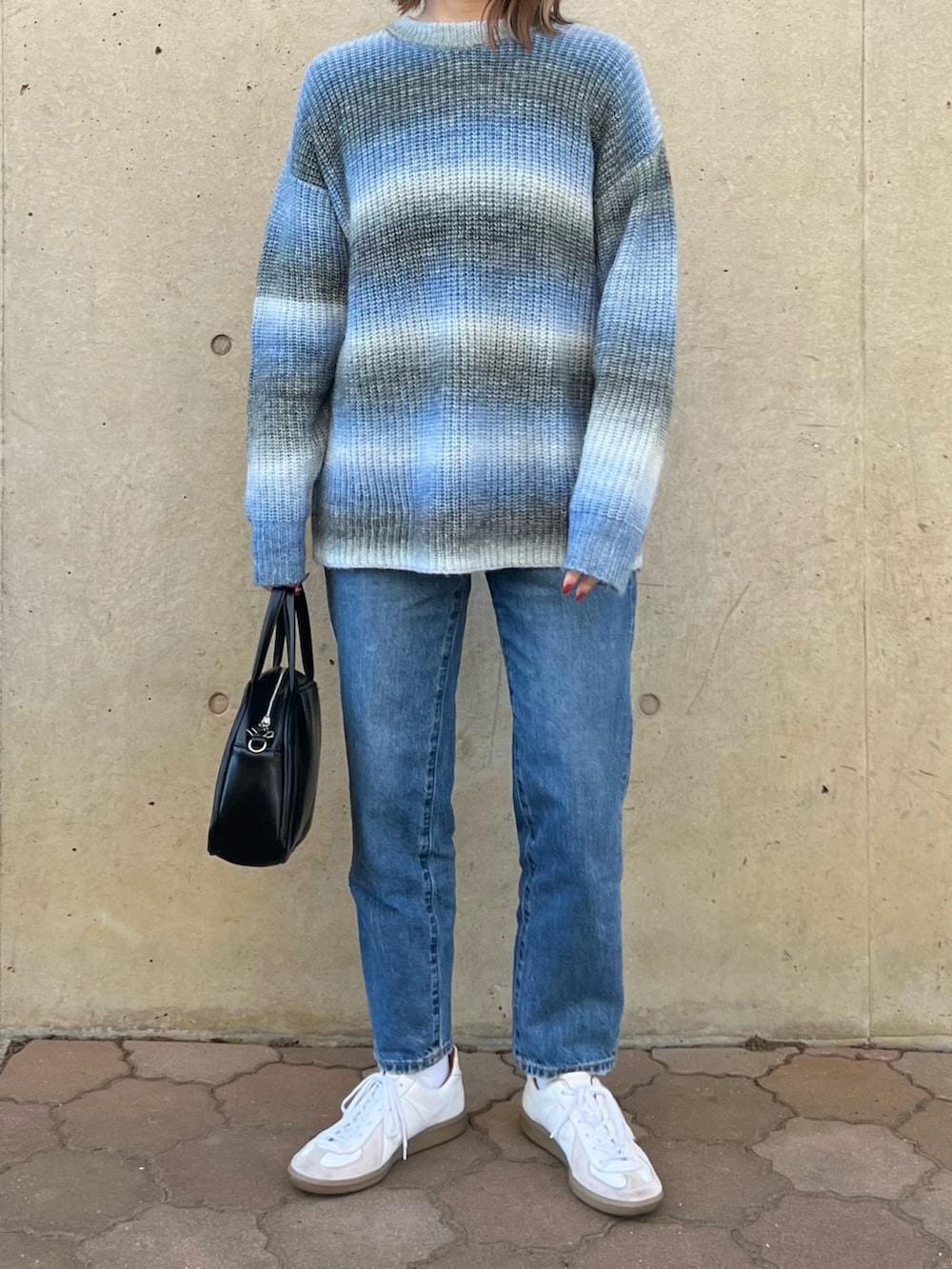 ブルー系のニット/セーター、ブラック系のボストンバッグ、ブルー系のデニムパンツを着用したレディースの冬コーディネートの3枚目の写真