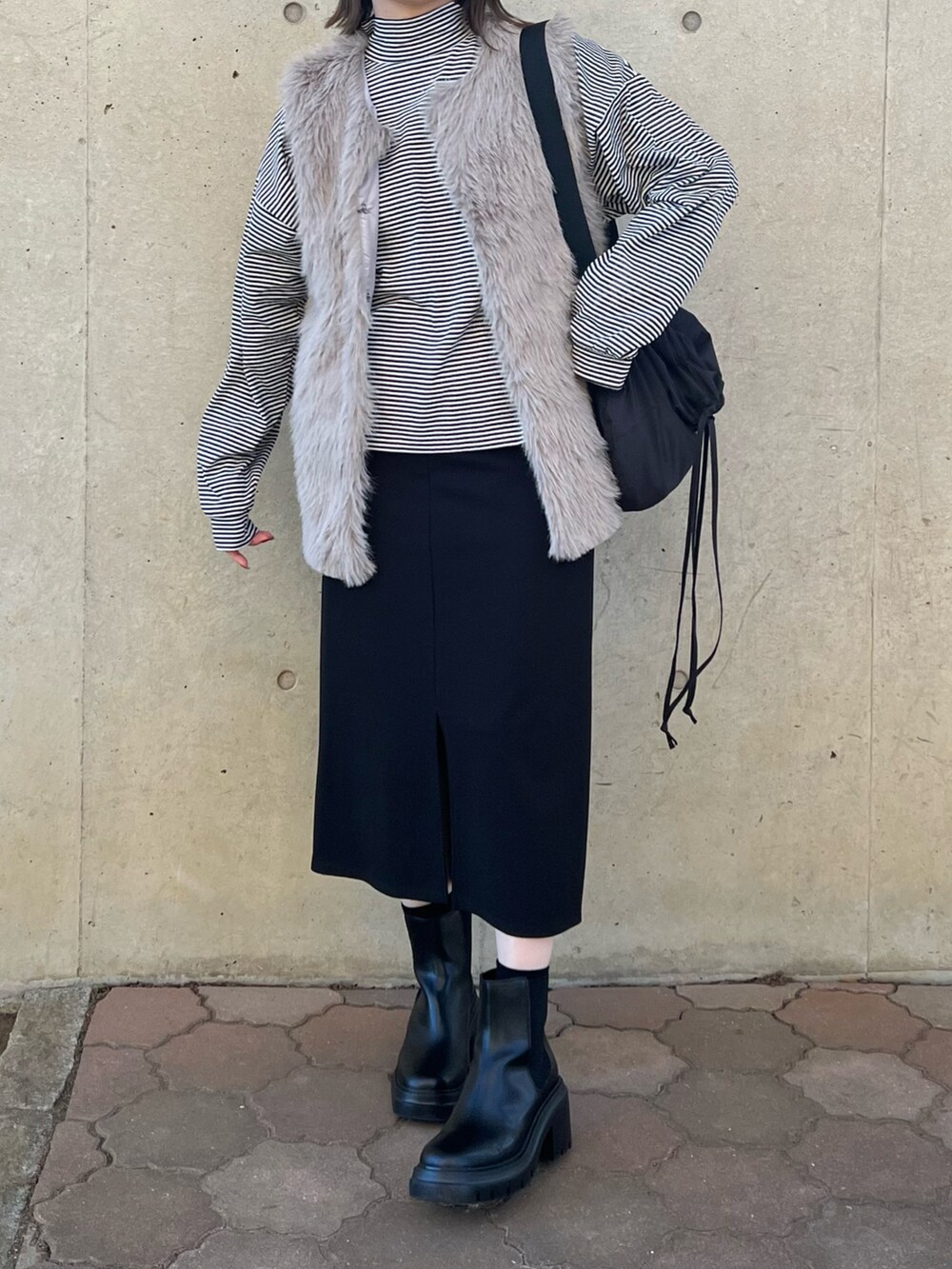 ブラック系のバッグ、ブラック系のジャンパースカート、ブラック系のブーツを着用したレディースの冬コーディネートの2枚目の写真