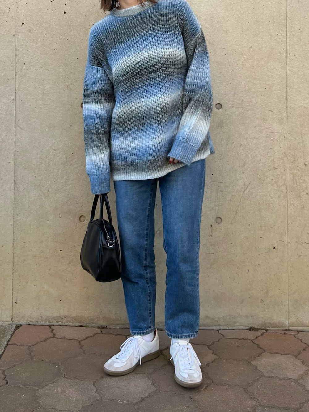 ブルー系のニット/セーター、ブラック系のボストンバッグ、ブルー系のデニムパンツを着用したレディースの冬コーディネートの2枚目の写真