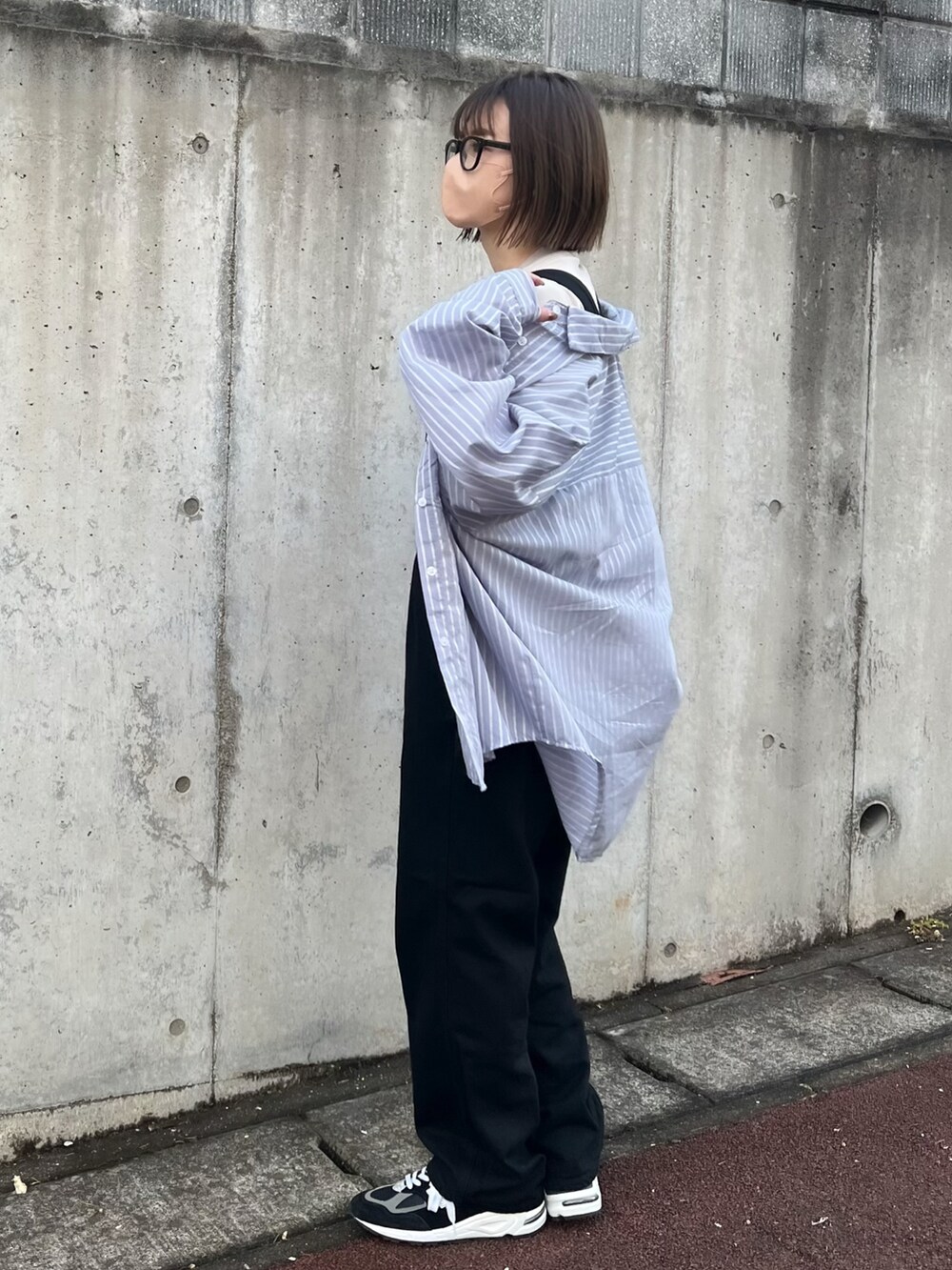 ブラック系のサロペット/オーバーオール、ブルー系のシャツ/ブラウス、ブラック系のスニーカーを着用したレディースの春コーディネートの2枚目の写真