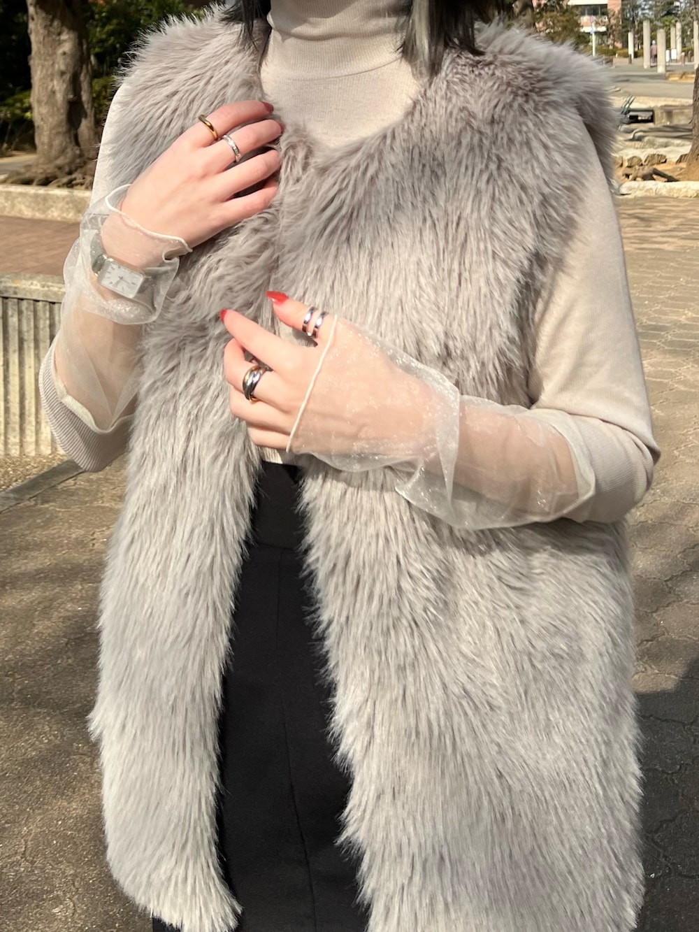 ベージュ系のTシャツ/カットソー、グレー系のベスト、ブラック系のジャンパースカートを着用したレディースの冬コーディネートの3枚目の写真