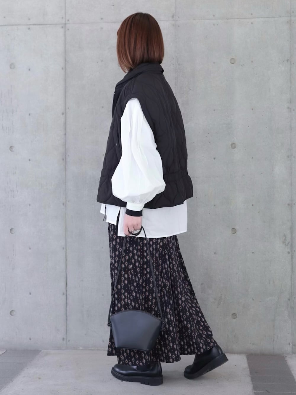 ホワイト系のシャツ/ブラウス、ブラック系のダウンベスト、ブルー系のスカートを着用したレディースの冬コーディネートの2枚目の写真