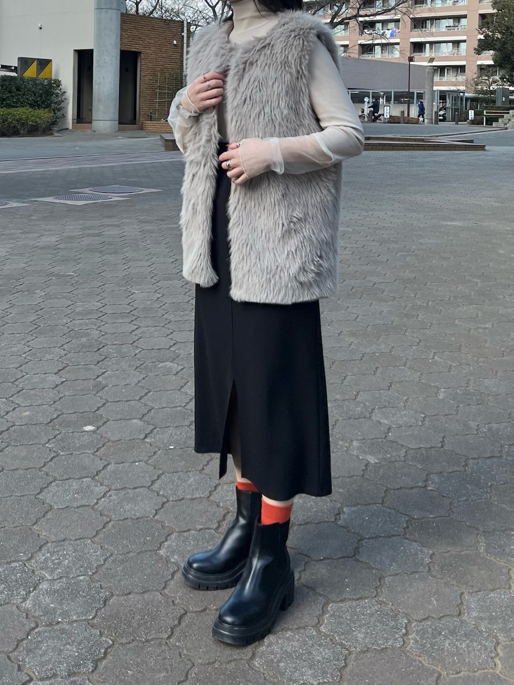 ベージュ系のTシャツ/カットソー、グレー系のベスト、ブラック系のジャンパースカートを着用したレディースの冬コーディネートの2枚目の写真