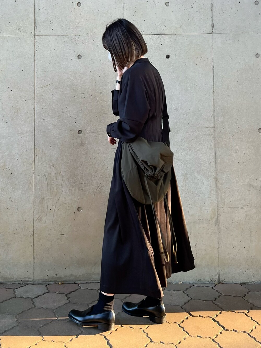 ブラック系のワンピース、グリーン系のショルダーバッグ、ブラック系のシューズを着用したレディースの秋コーディネートの2枚目の写真