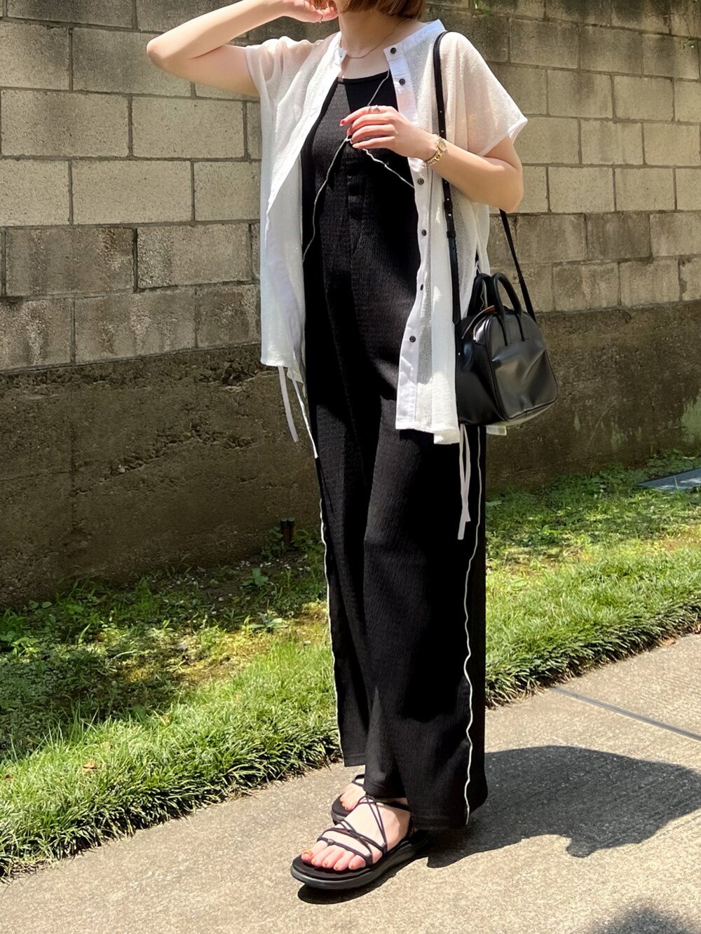 ブラック系のサロペット/オーバーオール、ホワイト系のシャツ/ブラウス、ブラック系のサンダルを着用したレディースの夏コーディネートの2枚目の写真
