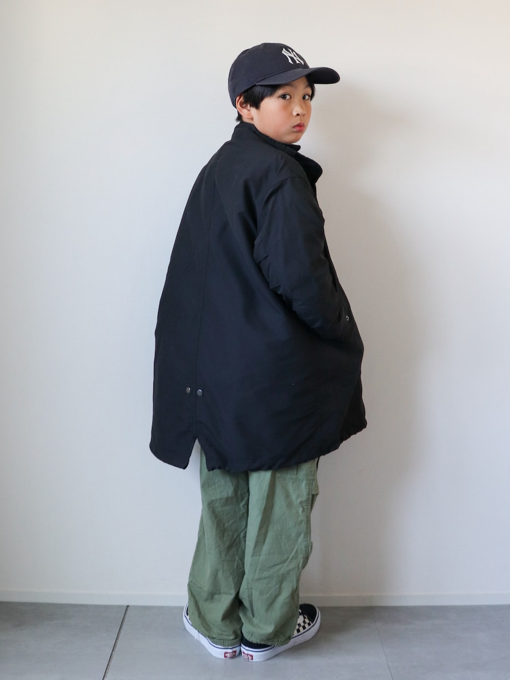 ブラック系のモッズコート、ブラック系のニット/セーター、ブラック系のシャツ/ブラウスを着用したキッズの冬コーディネートの2枚目の写真