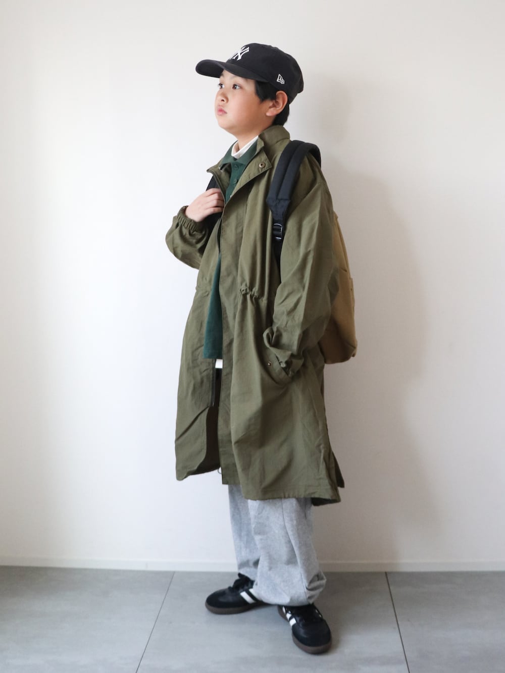グリーン系のテーラードジャケット、グリーン系のポロシャツ、グレー系のスウェットパンツを着用したキッズの冬コーディネートの2枚目の写真