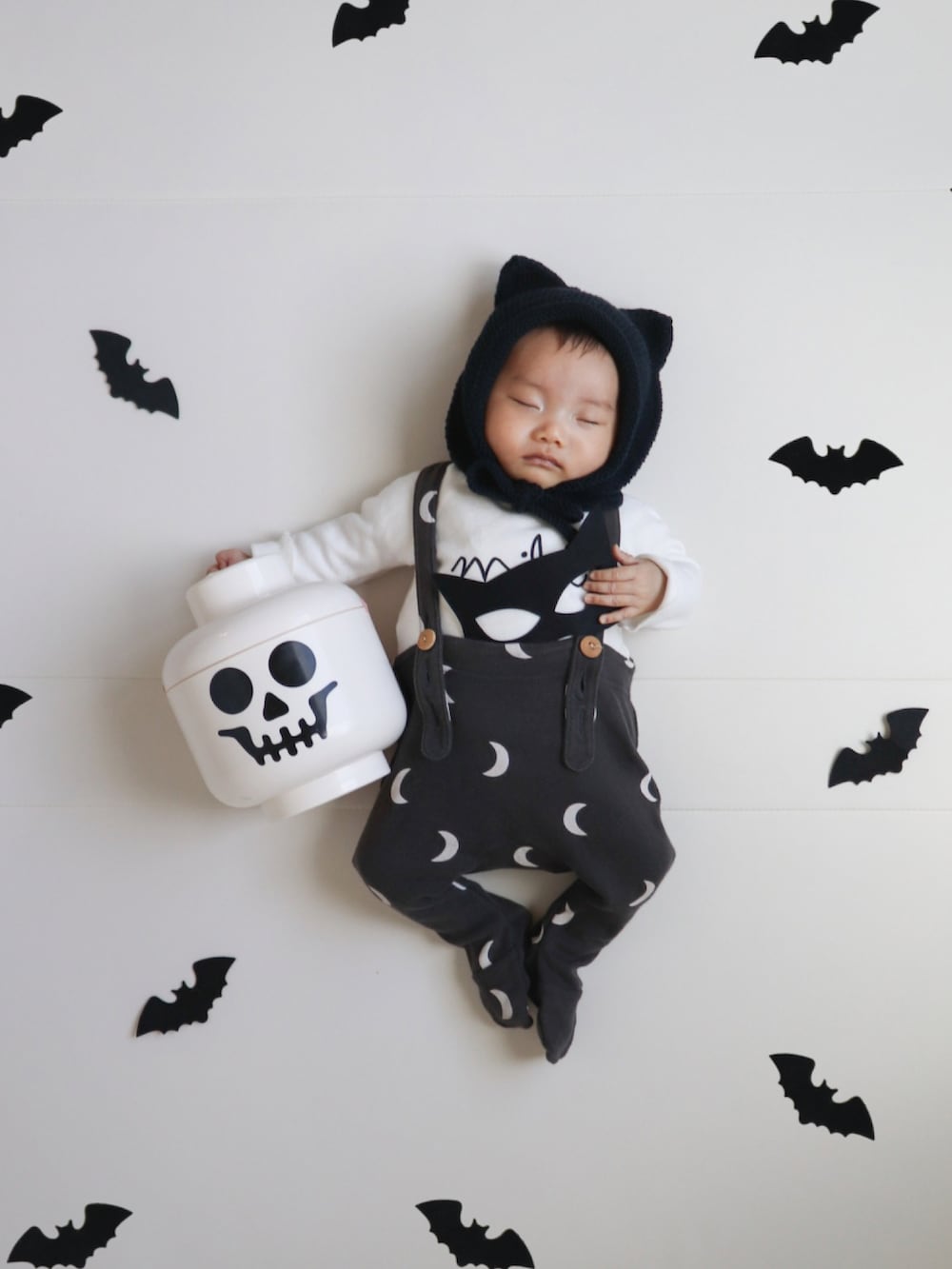 ブラック系の帽子、ベージュ系のロンパース、ブラック系のロンパースを着用したキッズの秋コーディネートの5枚目の写真