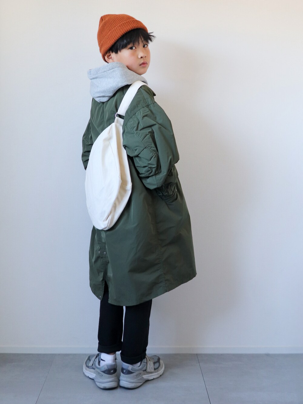 グリーン系のモッズコート、グレー系のパーカー、ブラック系のパンツを着用したキッズの冬コーディネートの2枚目の写真